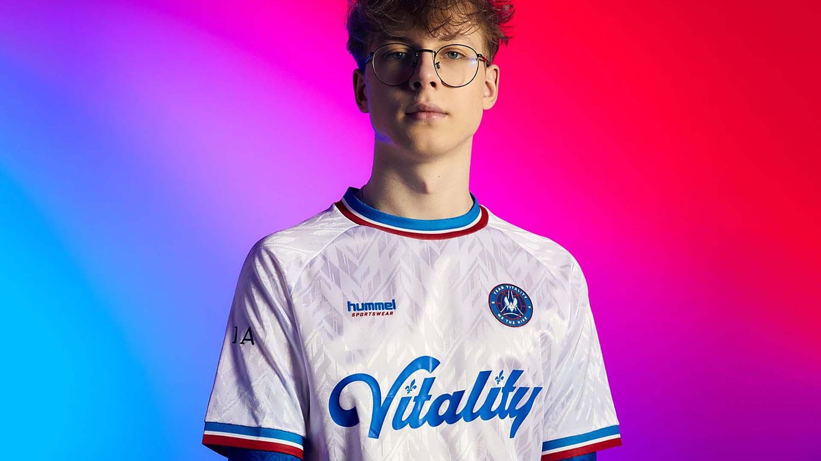 Image of person wearing red, white and blue Team Vitality jersey on a multicoloured background