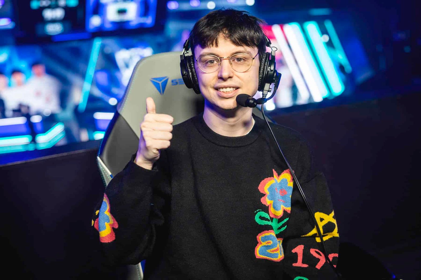Image of Caedrel smiling with a thumbs up. An esports stage is in the background